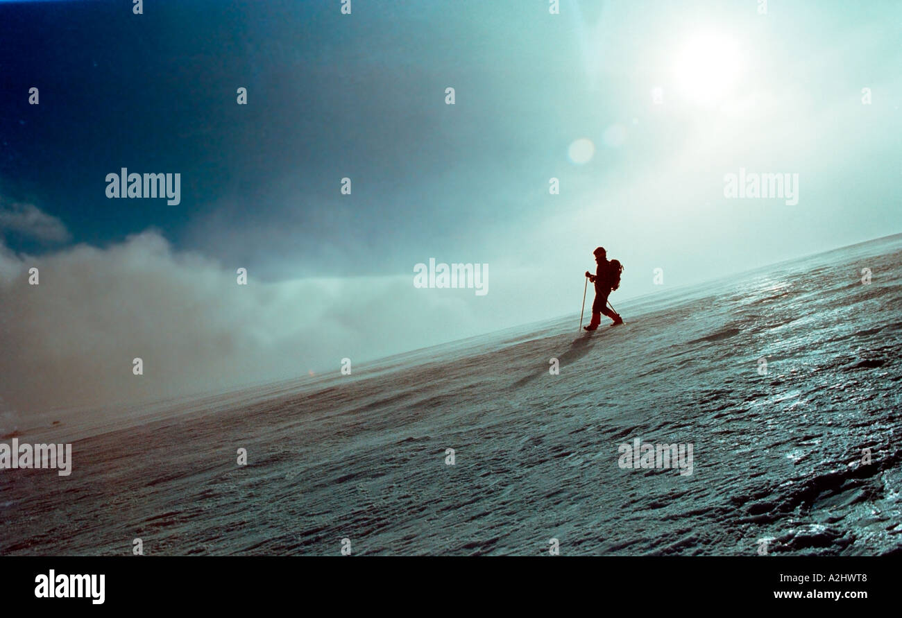 A mountaineer comes down the mountain over glossy ice sun and fog in background Stock Photo
