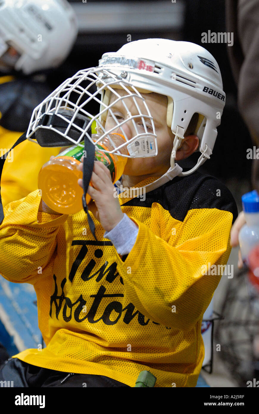 5 year old boys drinks gator aid for hydration and thirst as he learns how to play the game of ice hockey Stock Photo