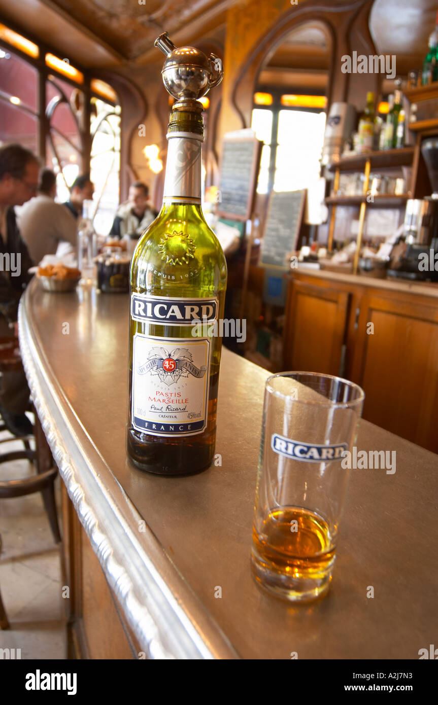 A bottle of Ricard 45 pastis and a glass on a zinc bar in a cafe