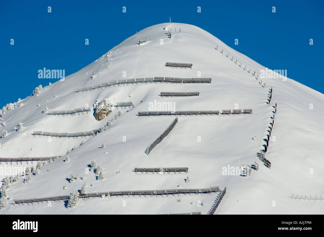avalanche protection barriers on a snow slope in the alps Stock Photo