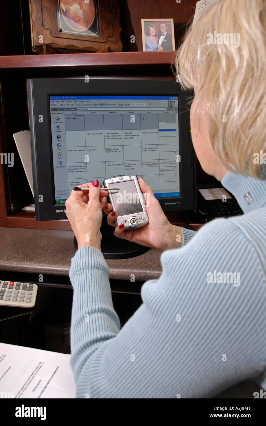 Adult female professional uses a PDA to organize and synchronize her
