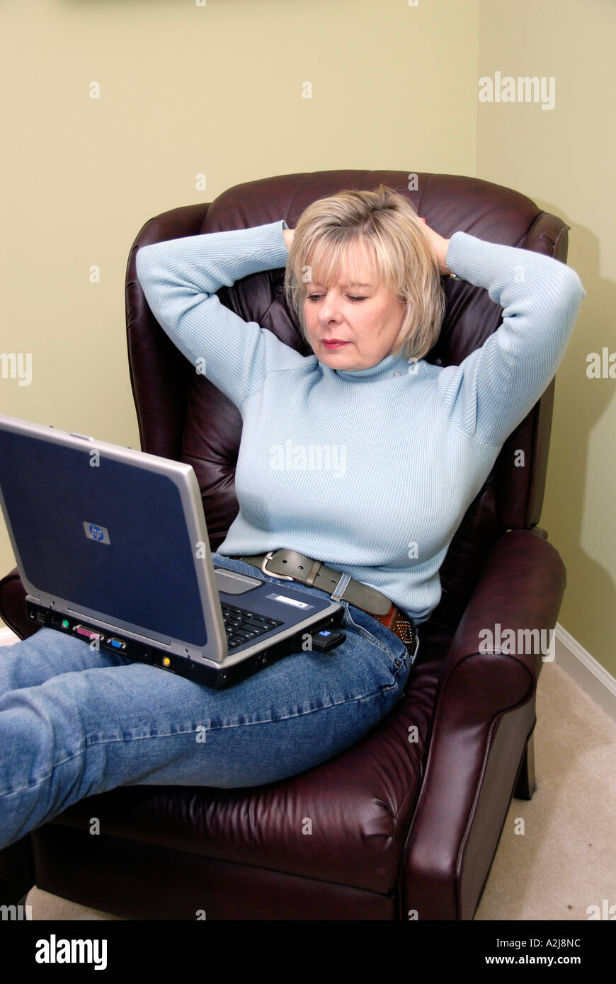 Relaxed Computer User Female relaxes using a laptop computer and a wireless connection to the ...