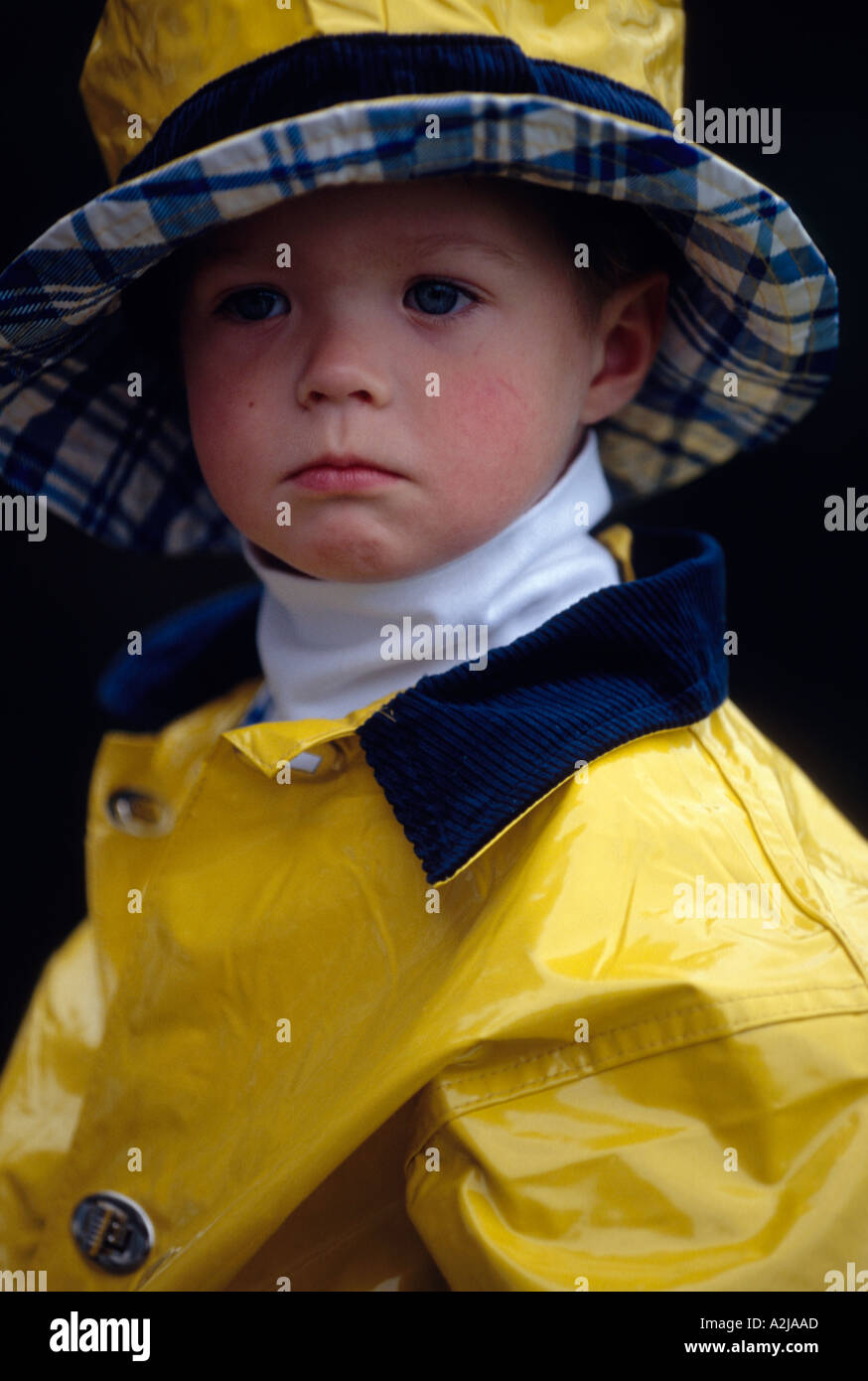 Portrait of a serious child wearing a yellow rain hat and matching slicker  Stock Photo - Alamy