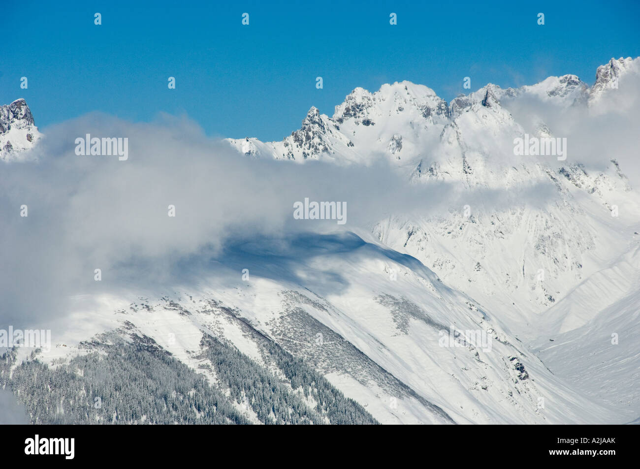 high snow covered mountains with low cloud in wintertime Stock Photo ...