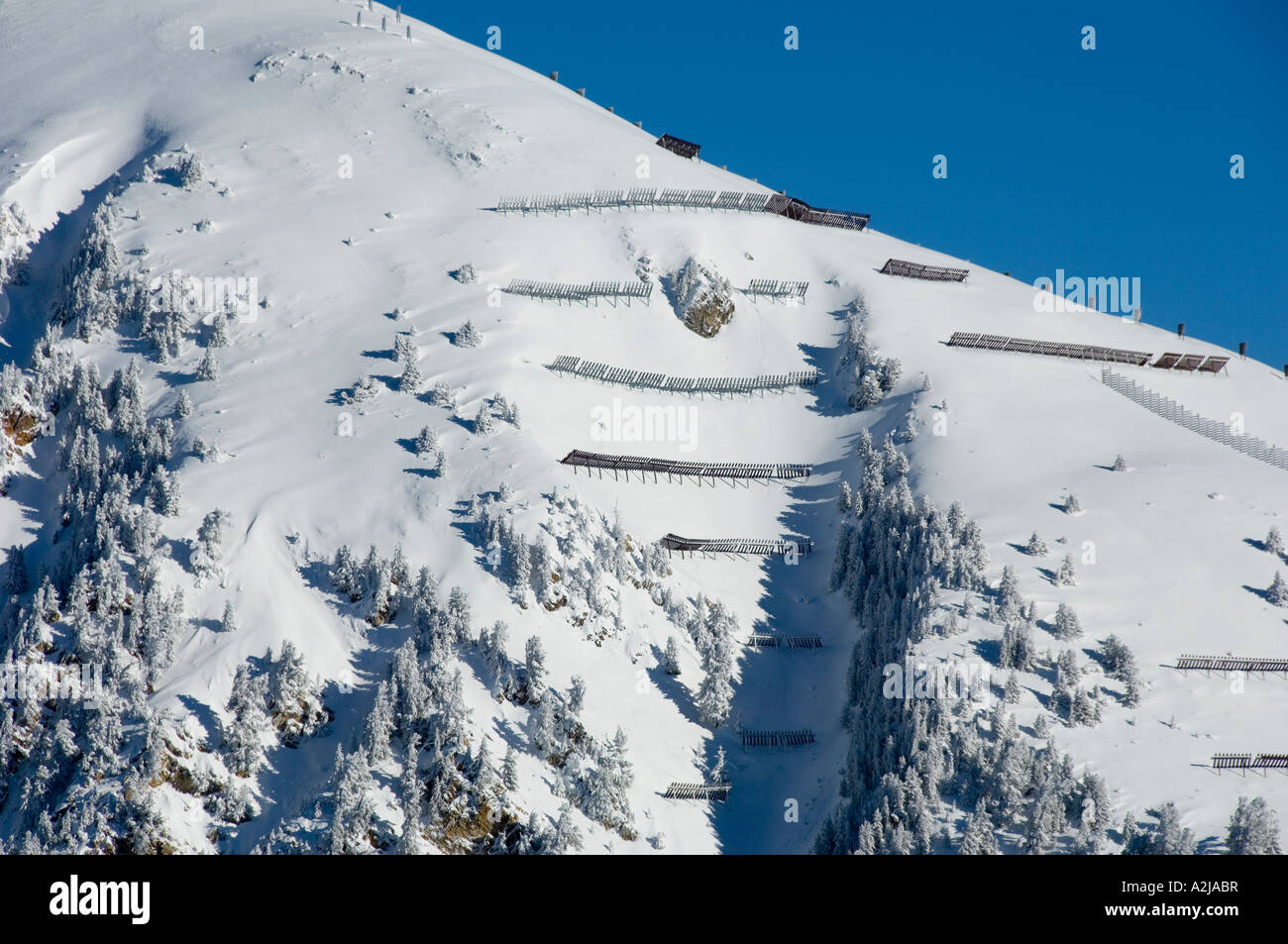 Avalanche protection barriers on a snow filled gully in the alps Stock