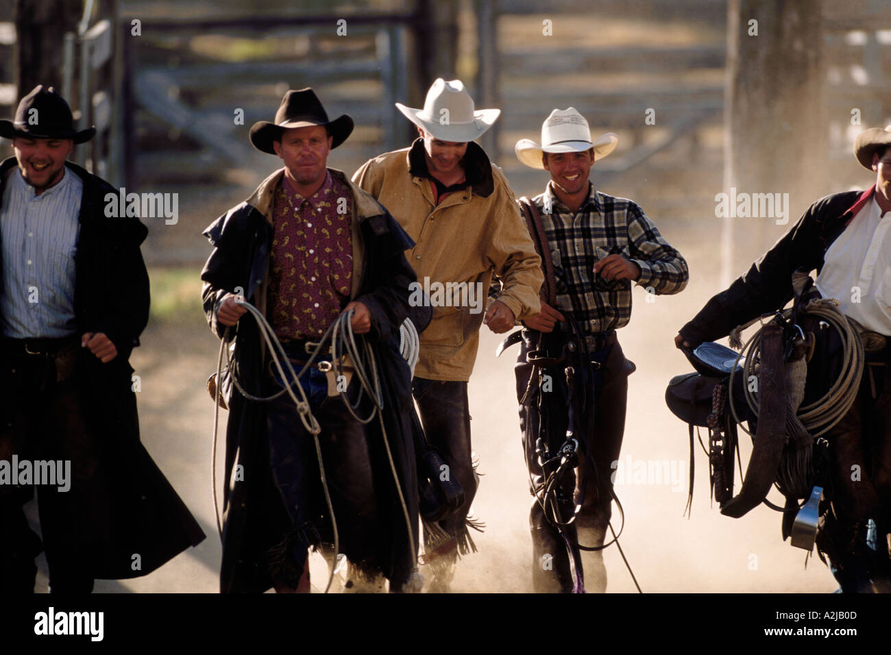 Five working cowboys carry their saddles ropes and equipment across a ...