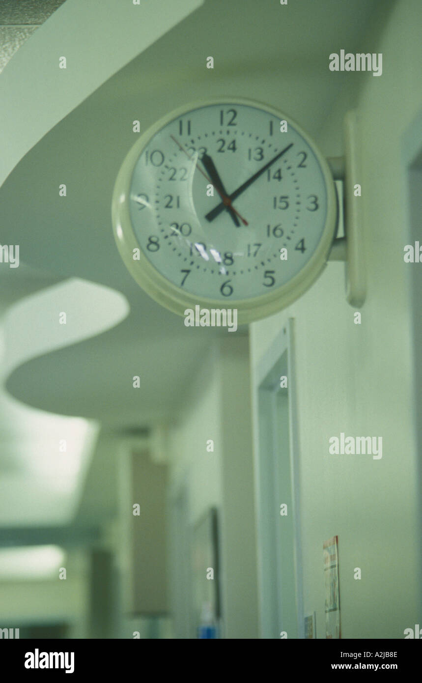 A clock is set high up on the wall of a hospital corridor Stock Photo