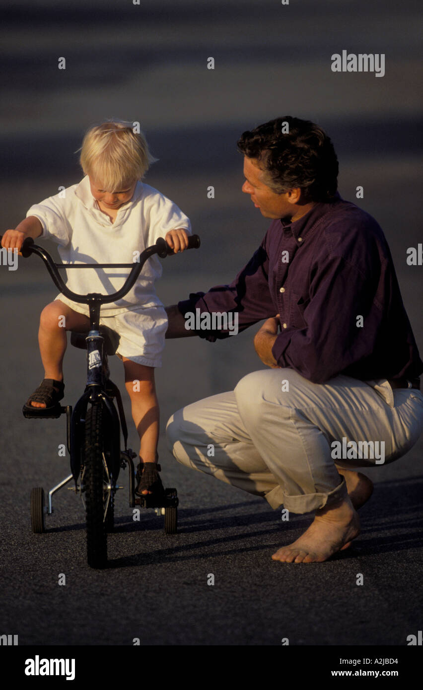 Young boy concentrates on balancing his bicycle with training wheels as