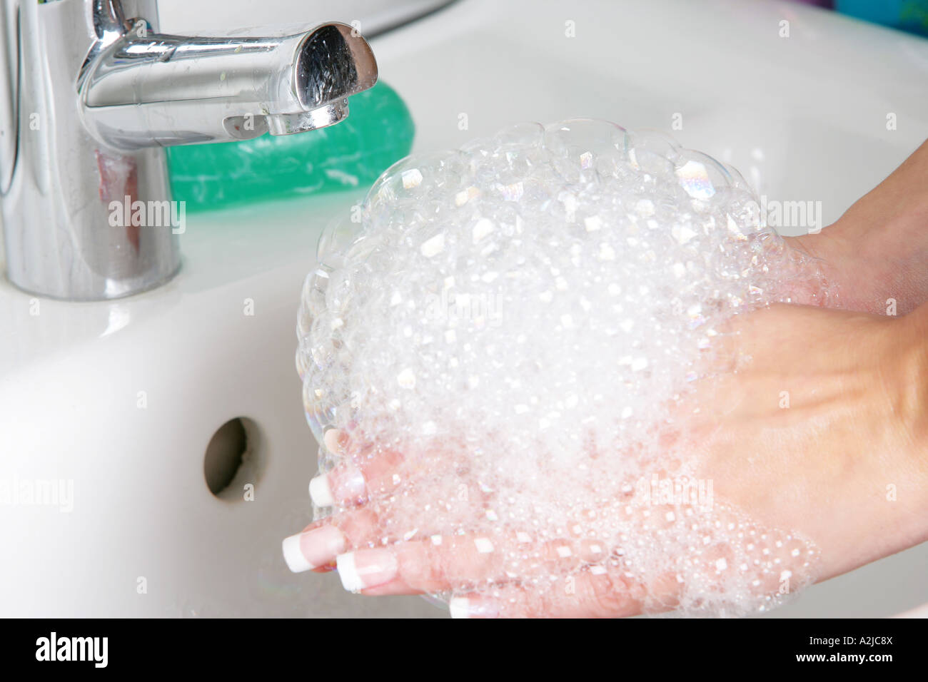 Young Woman Washing Her Hands In A Bathroom Sink With Soap And Water ...