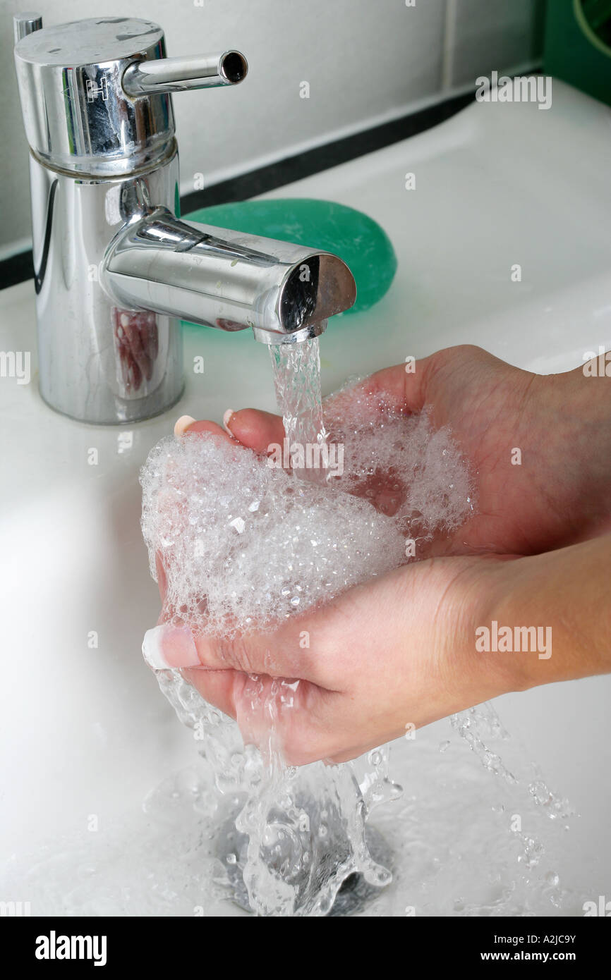 Young Woman Washing Her Hands In A Bathroom Sink With Soap And Water ...