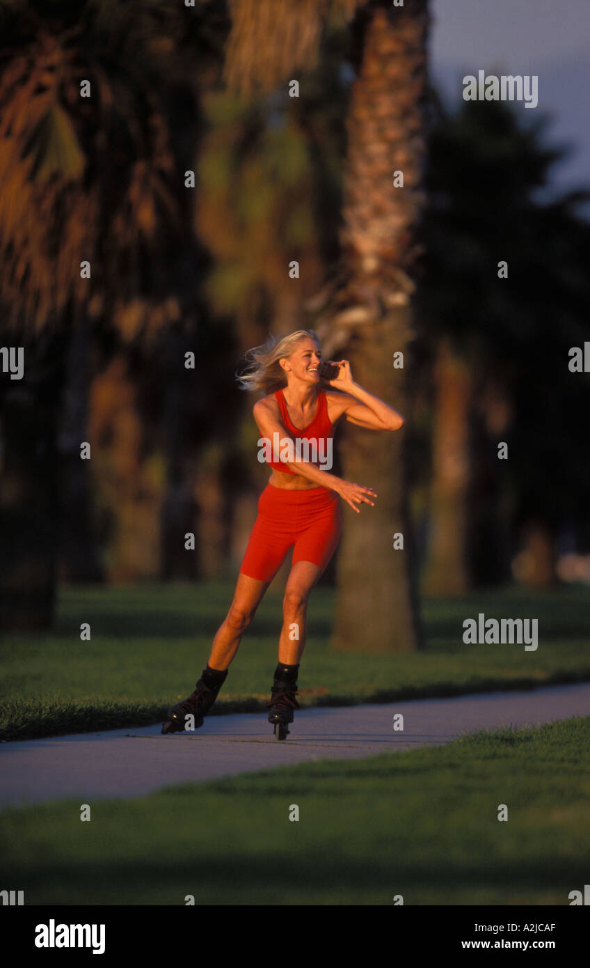 Woman without helmet or pads rollerblading down a park sidewalk while