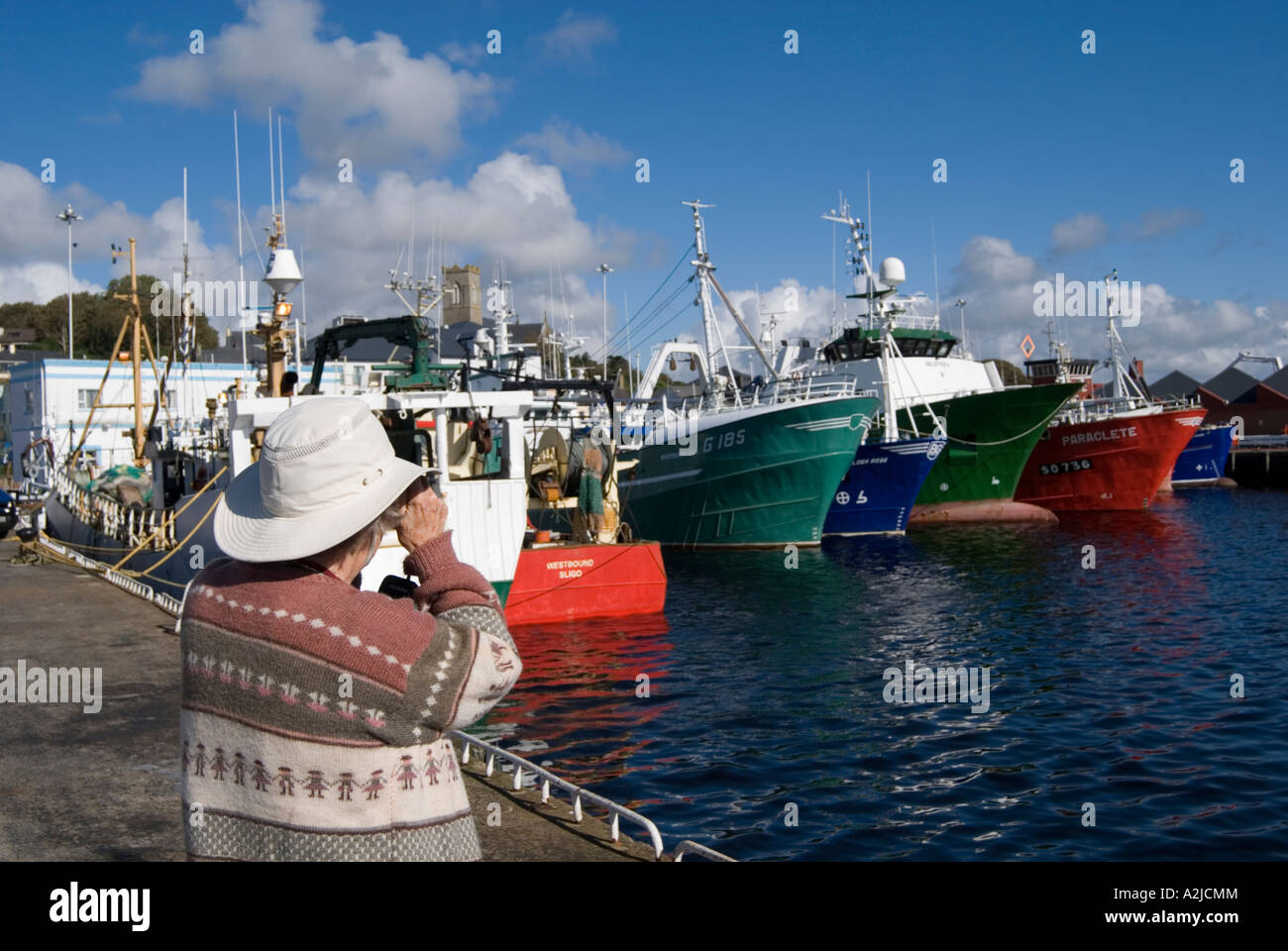 A tourist photographs fishing boats in the harbour Stock Photo