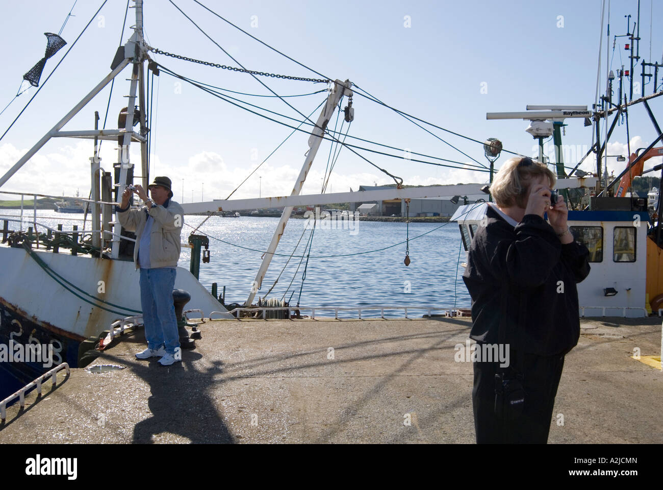 Tourists photograph fishing boats in the harbour Stock Photo