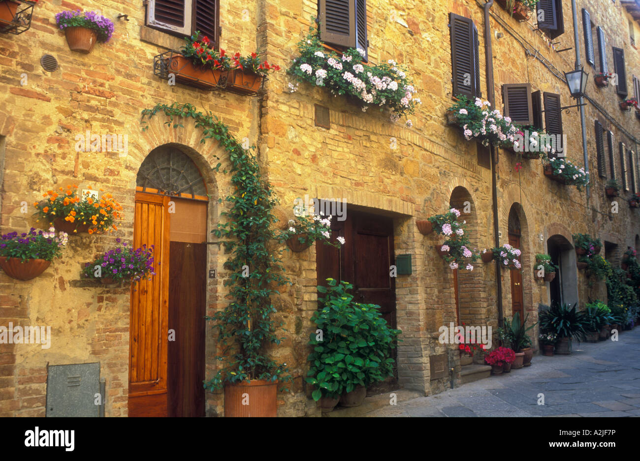 Italy Pienza Tuscany hanging flower baskets along a brick wall with