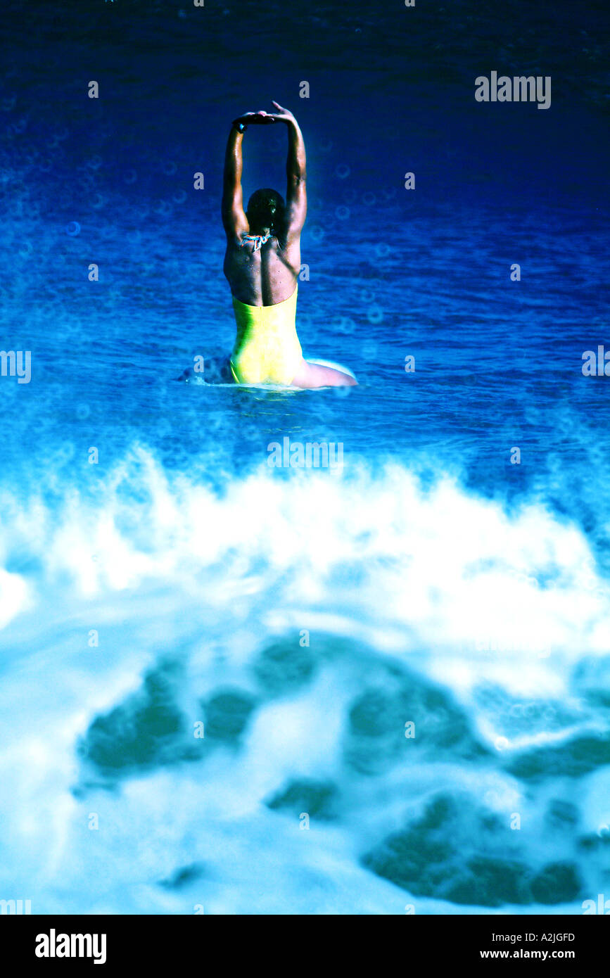 Female surfer age 20-25 sitting on her surf board. The image is color and was taken in Brazil. Stock Photo