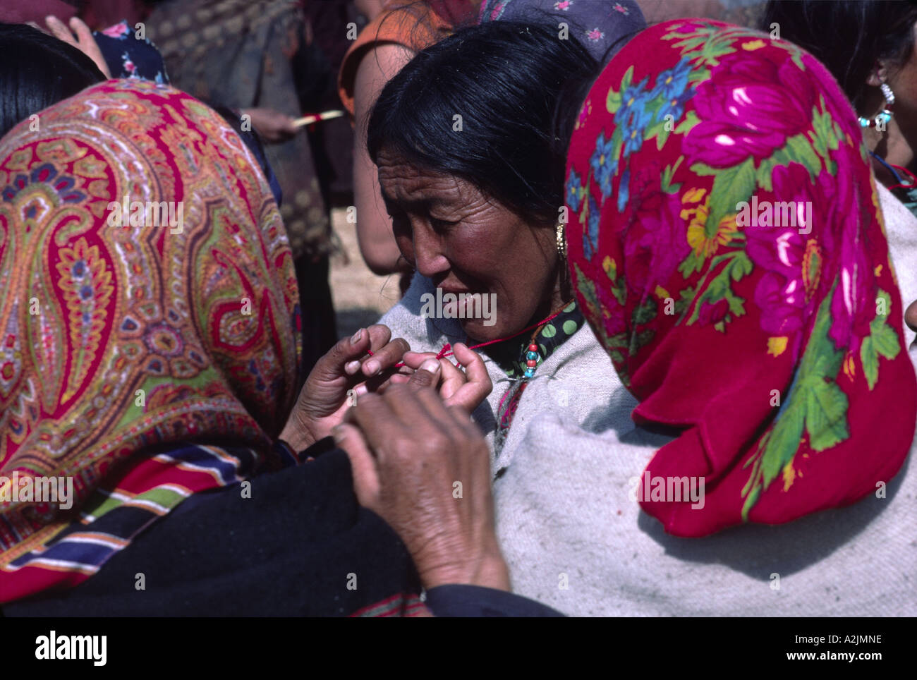 A Buddhist pilgrim from Tibet having a sacred thread tied around her ...