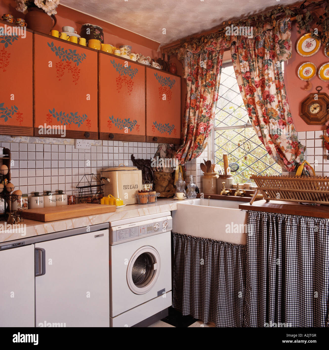 Stencilled Cupboards And Floral Curtains In Small Kitchen With