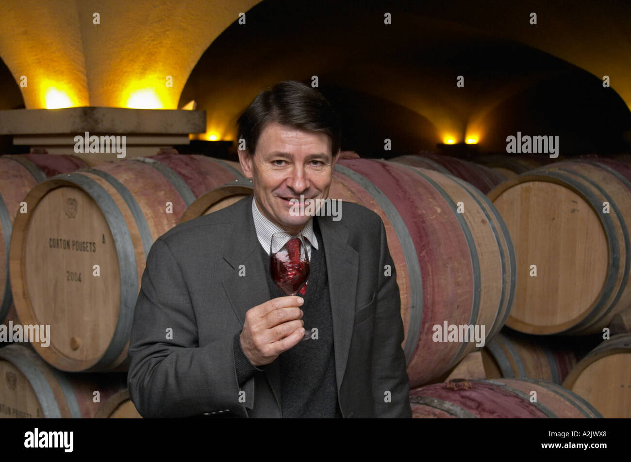 The old style vaulted barrel aging cellar with barriques pieces with maturing wine. General Manager Pierre-Henri (Henry) Gagey posing in front of barrels with a glass of wine., Maison Louis Jadot, Beaune Côte Cote d Or Bourgogne Burgundy Burgundian France French Europe European Stock Photo