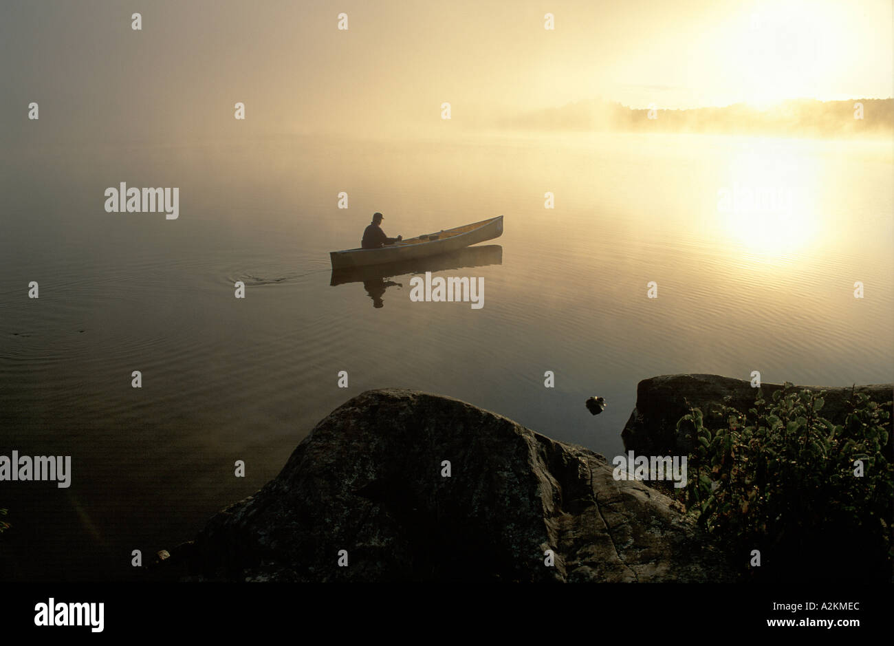 man in a canoe paddling across a lake Stock Photo - Alamy