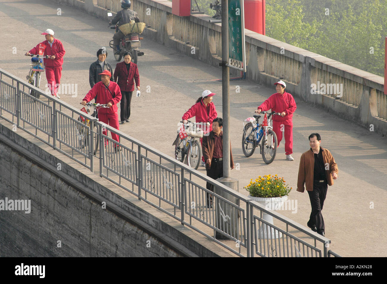 workers riding bycicles and pedestrians crossing a bridge Stock Photo
