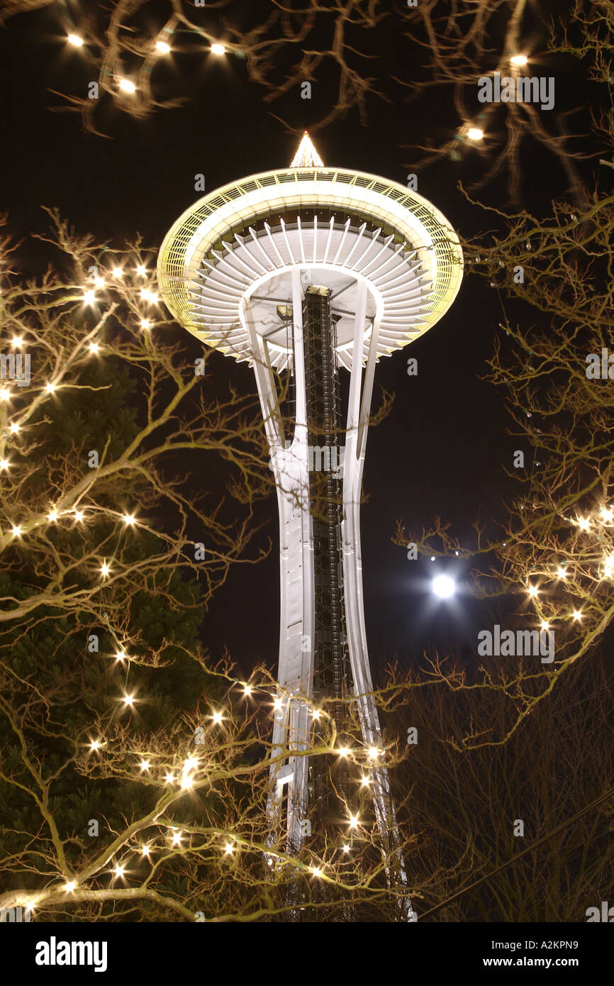 Nighttime scene of Seattle Space Needle and full moon through branches