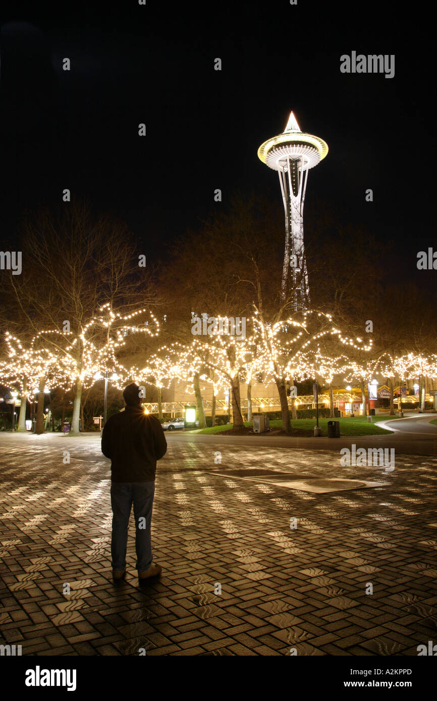 Nighttime scene of man standing on walkway in Seattle Center decorated