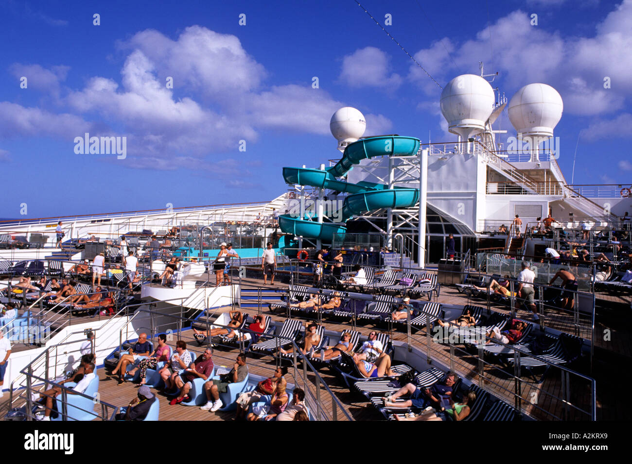 Crowded Carnival Liberty Cruise ship in the Caribbean with everyone around the pool and water slide Stock Photo