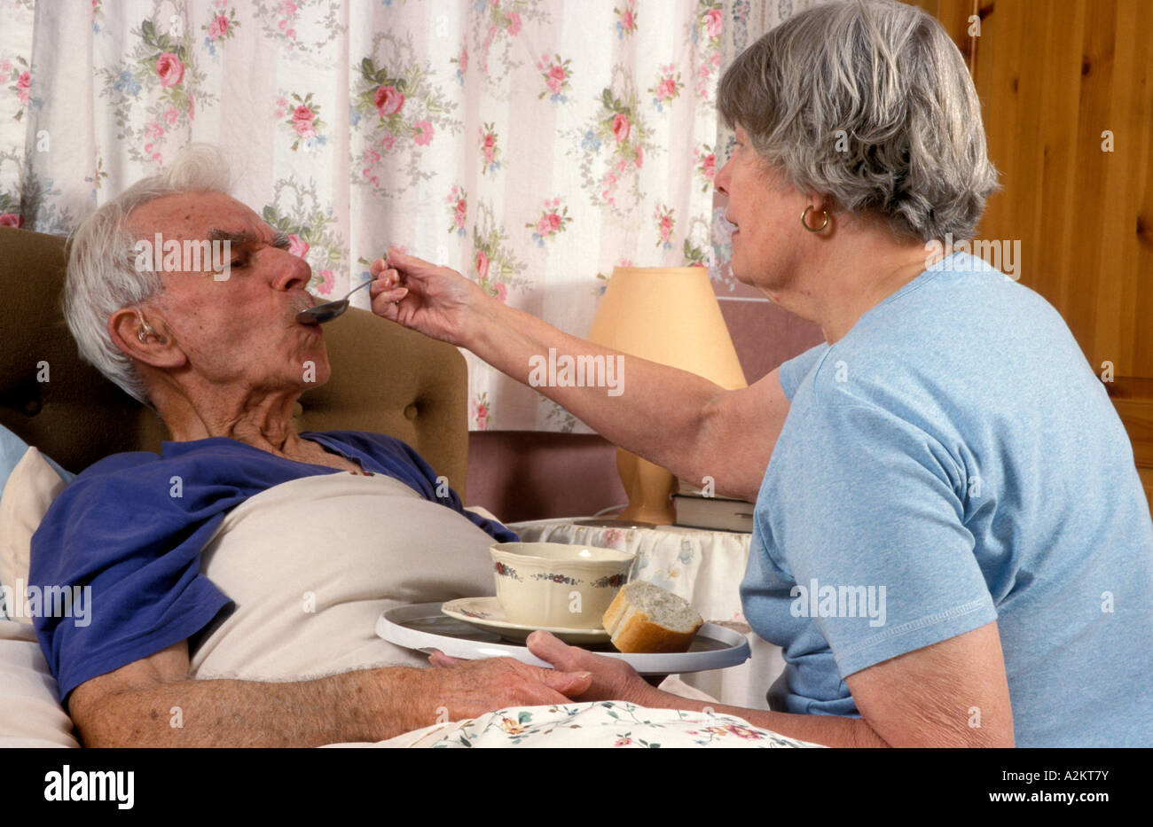 mature woman spoon feeding soup to sick elderly man Stock Photo