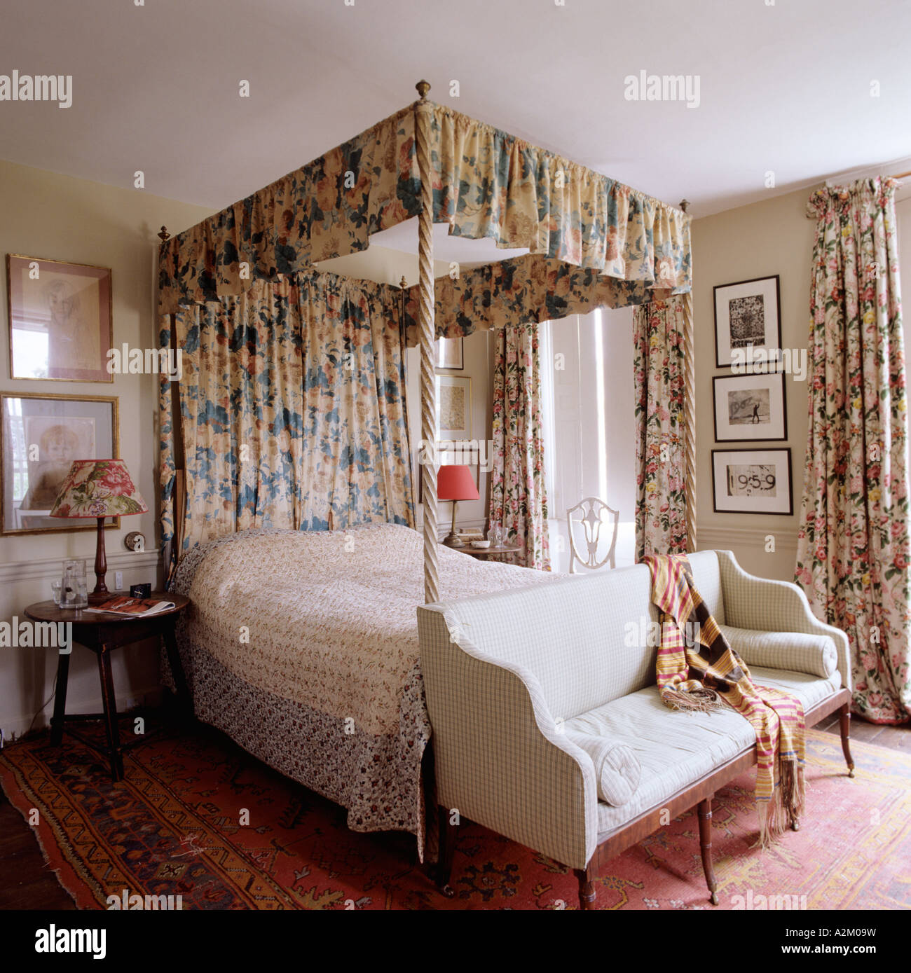 Bedroom with fourposter bed with floral curtains and settee with bolster Stock Photo