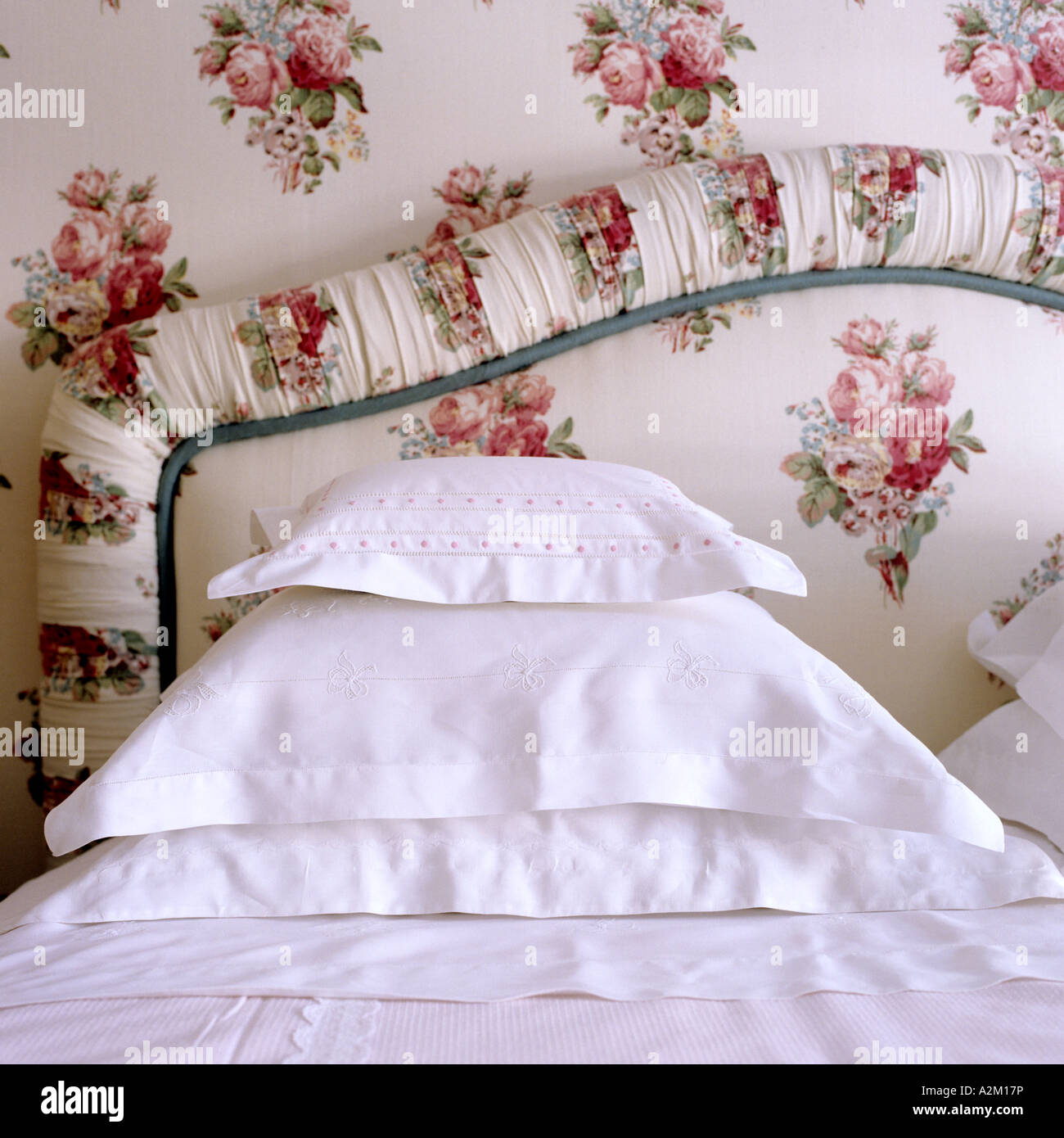 fabric-covered bed head and pillows in crisp white cotton slips Stock Photo