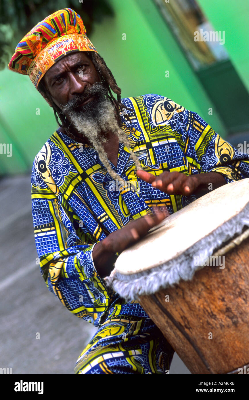 Colorful Rasta Jamaican Reggae performer on drum in costume at Harbour in St John Antigua Stock Photo