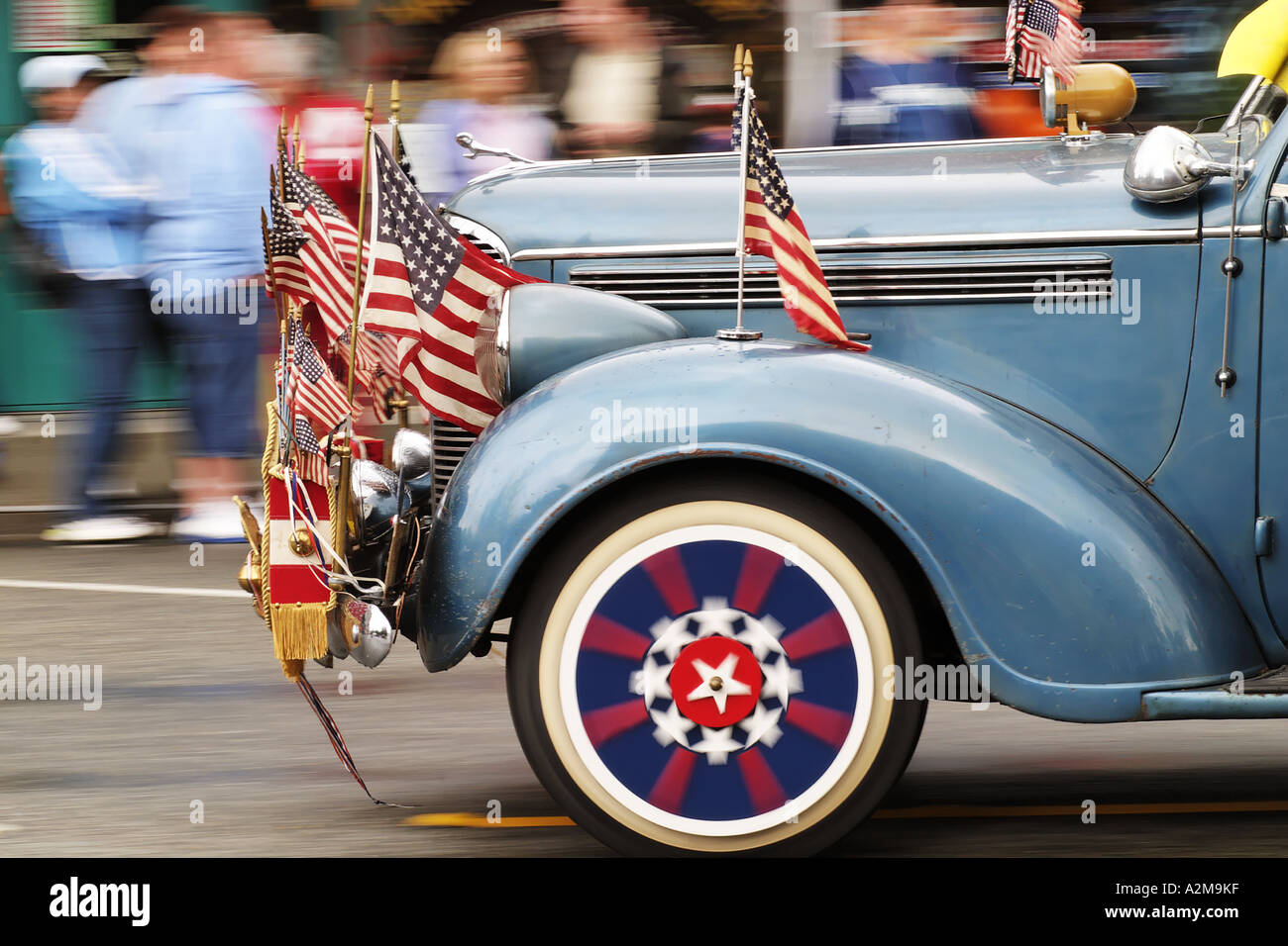 Classic car adorned with US flags and regalia driving in parade to