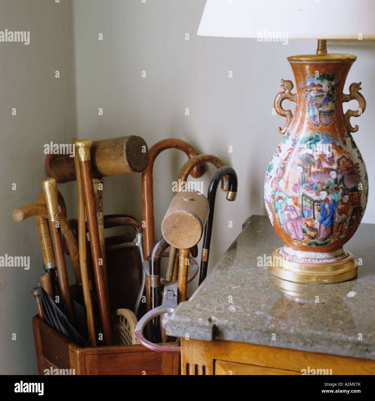 Decorative lamp stand on marble top next to umbrella stand with a collection of old fashioned walking sticks Stock Photo