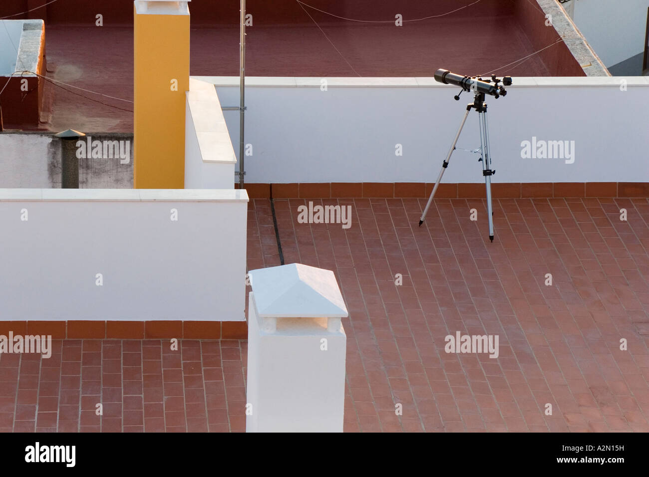 A telescope on a tripod on a red tiled roof Stock Photo