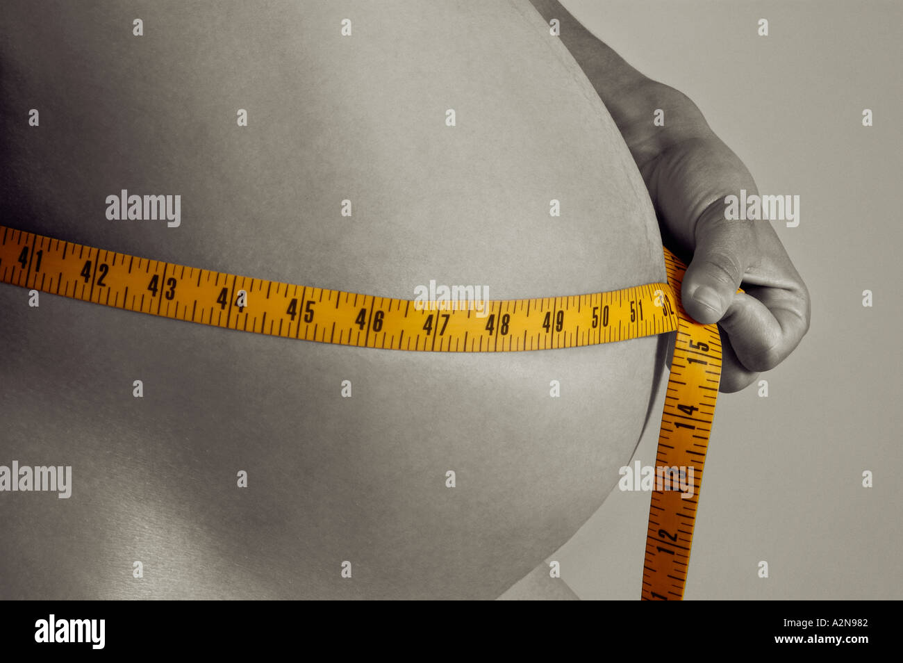 PREGNANT WOMAN MEASURING HER ABDOMEN WITH A MEASURING TAPE. PREGNANCY