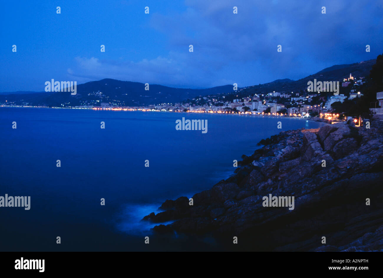 Town at the coast lit up at night, , Italian Riviera, Mar Ligure, Genoa, Liguria, Italy Stock Photo