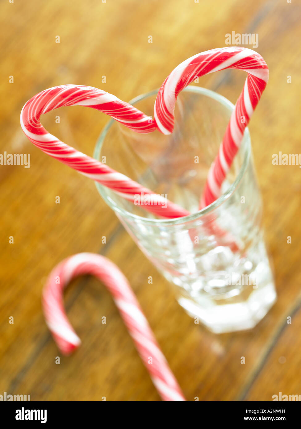 red and white candy cane sticks making a symbol of a hart shape in a glass tumbler Stock Photo