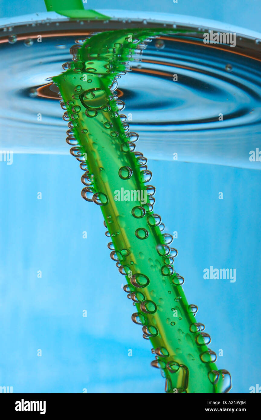 Green straw in glass of water Stock Photo