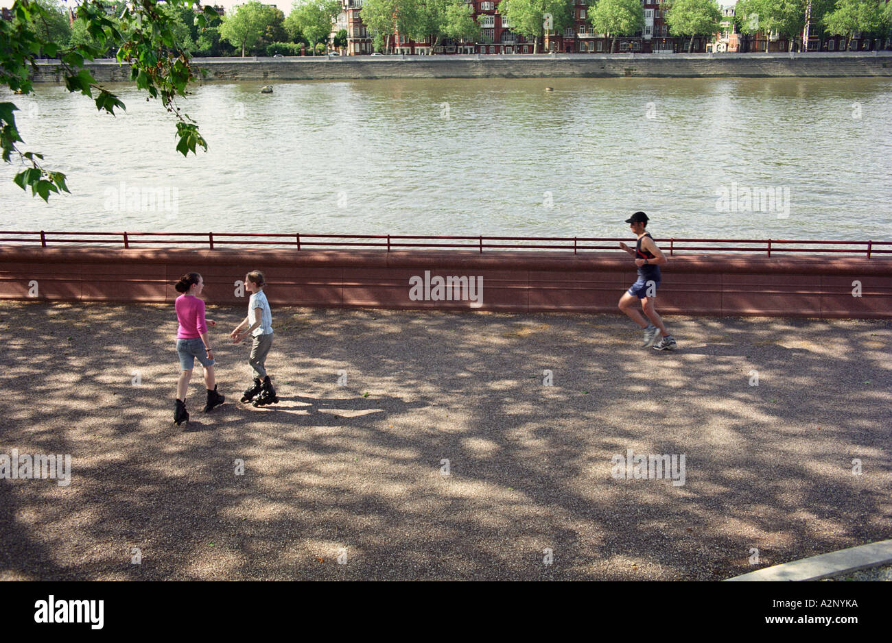United Kingdom, England, London. Battersea Park alongside the river Thames. Young people roller skating. Man jogging Stock Photo