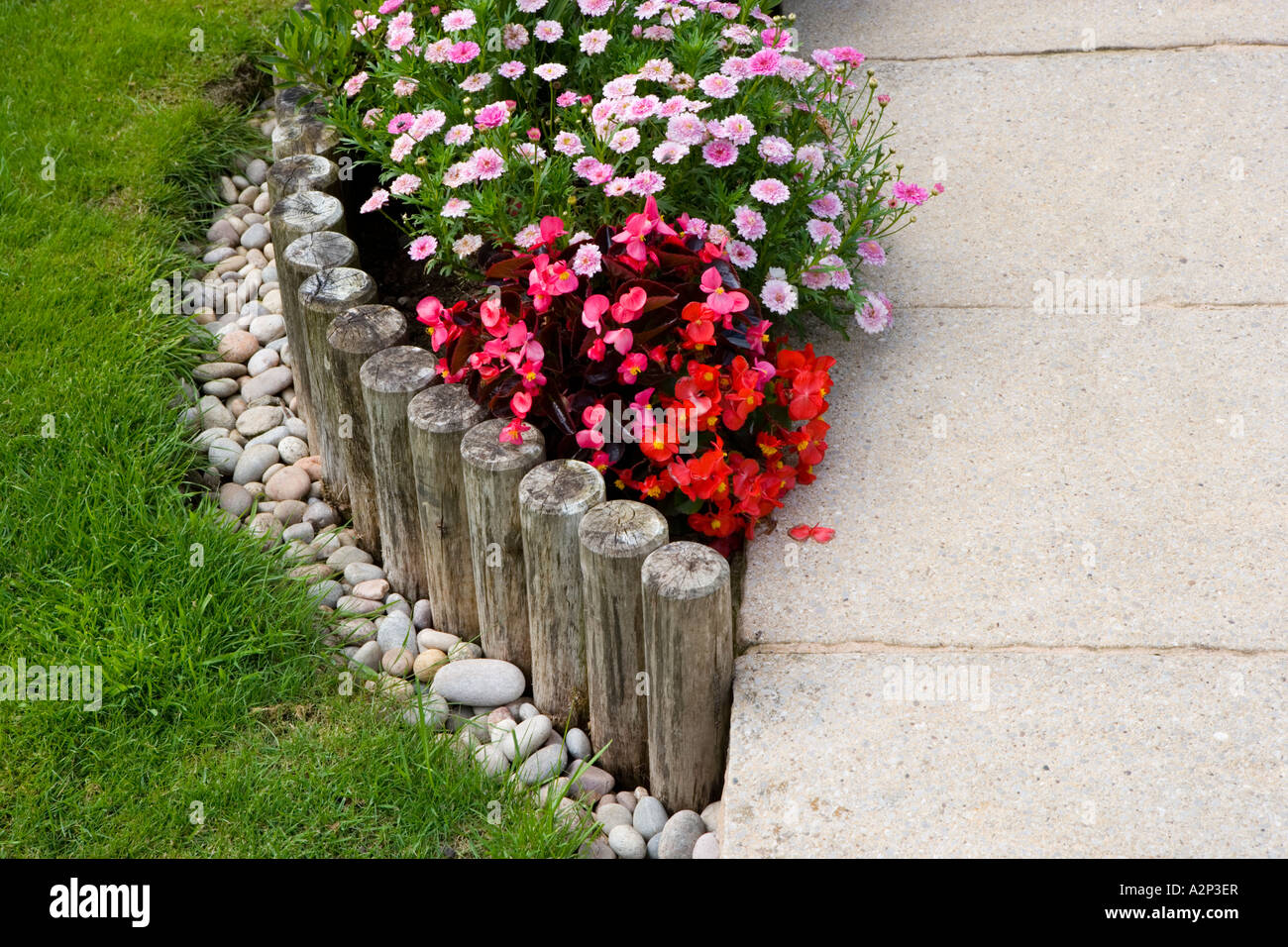 Wooden posts edging a flower bed with begonia Stock Photo