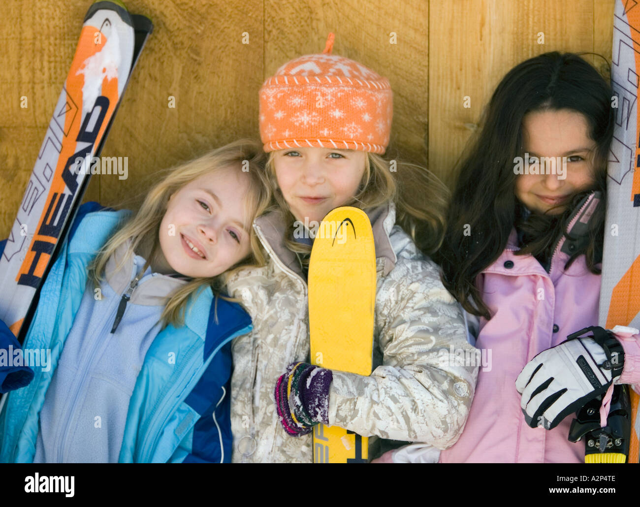 Three girls wearing ski outfits and holding skis Stock Photo Alamy