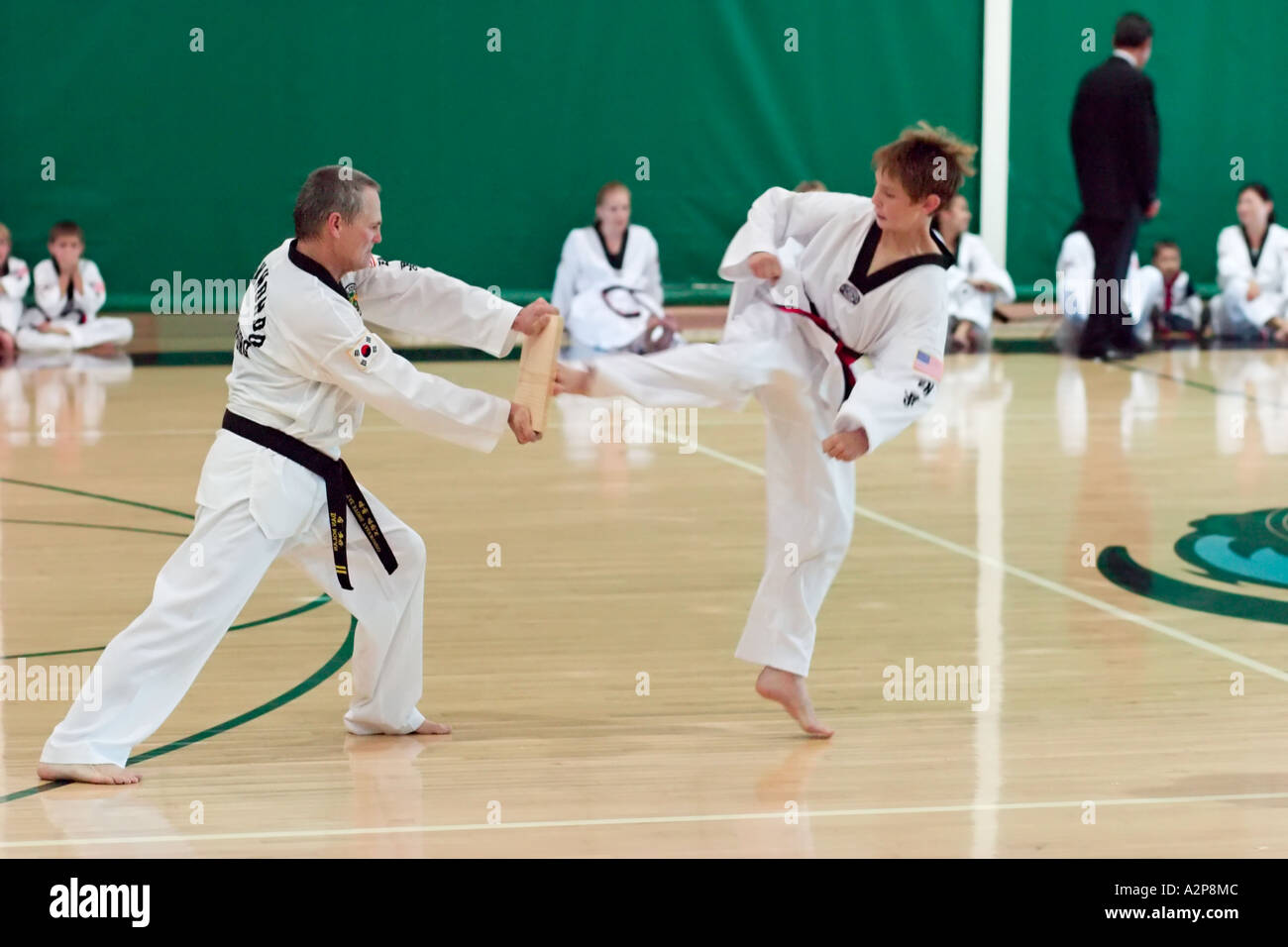 A young boy breaks a wood board with a powerful kick during Tae Kwon Do