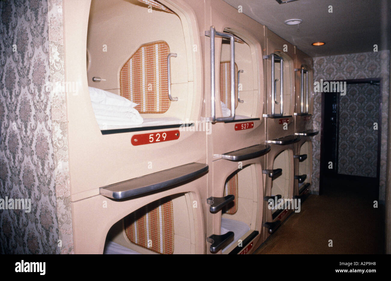 Looking down corridor fulll of numbered sleeping capsules inside Gotanda Business Hotel Stock Photo