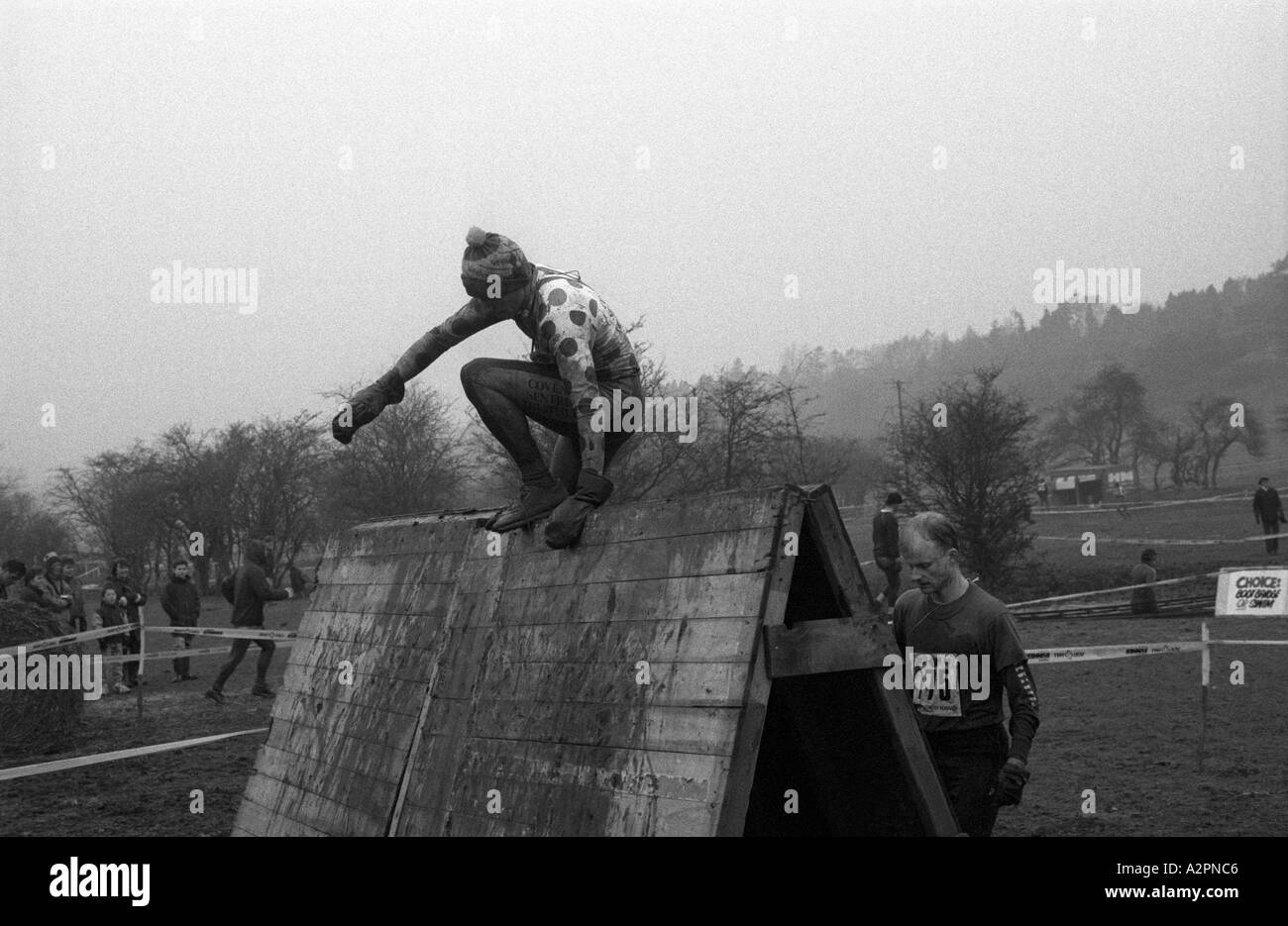 Competitor climbing over obstacle in Tough Guy Race 1991 at Tettenhall, West Midlands, England, UK Stock Photo