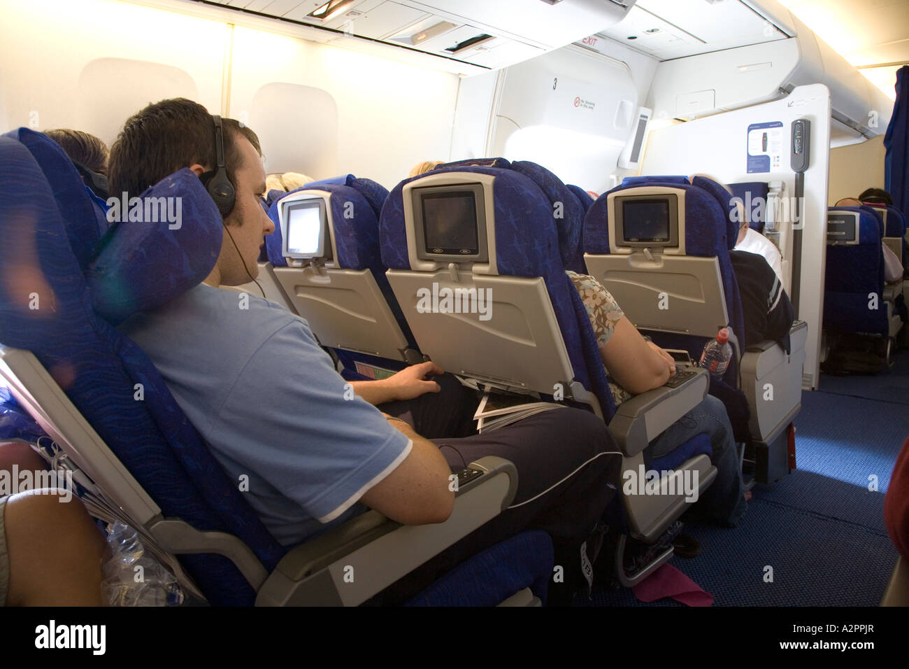Passenger wearing headphones on a long haul flight Stock Photo