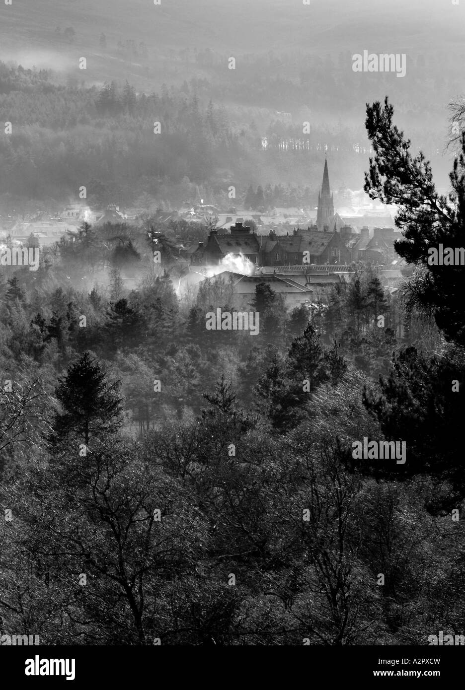 A moody black and white portrait format image of Ballater, Scotland looking down from Craigendarroch in winter. Stock Photo