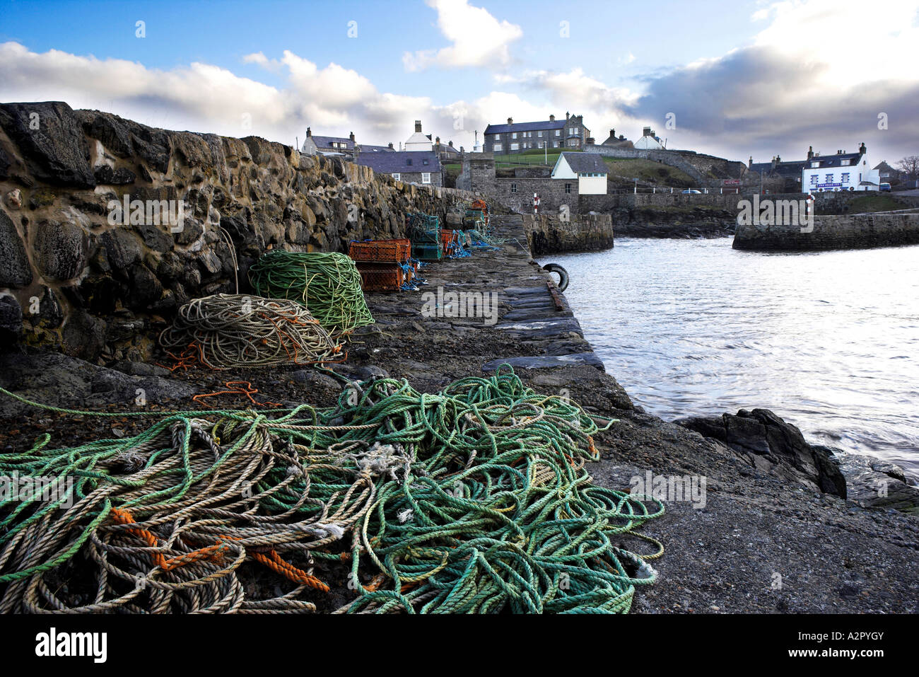 Portsoy Old harbour on the Banffshire coastline, North East Scotland with fishing nets and ots in foreground. Stock Photo