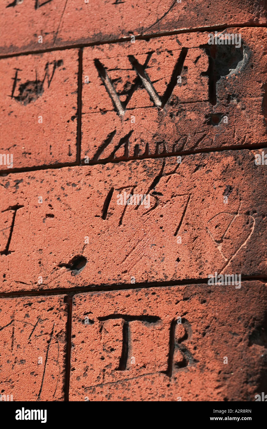 Graffiti craved in brickwork on old school walls Dedham North Essex UK Great Britain England Stock Photo