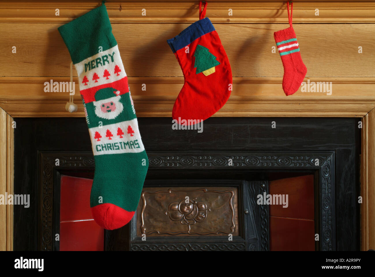 Three different sized Christmas stockings hanging over a fireplace