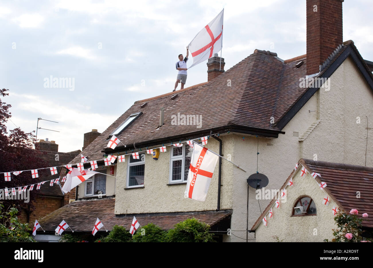 An England football fan shows his support by stringing up patriotic flags outside his house in Redditch Worcestershire UK Stock Photo